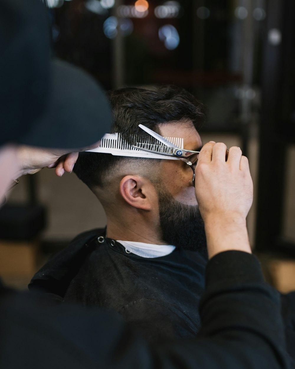 Barbier formt mit Kamm und Schere den Bart eines Kunden