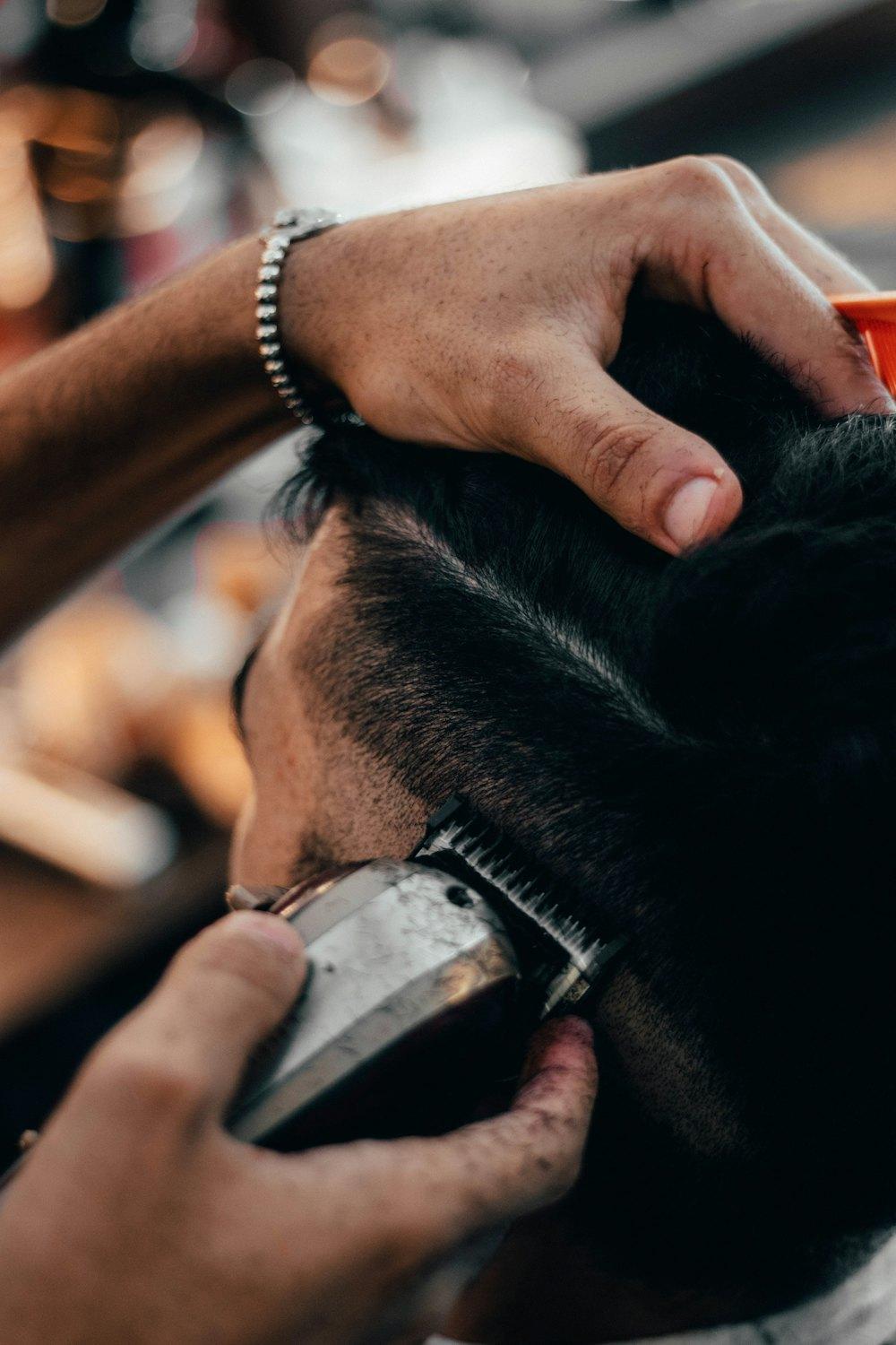 Barbier schneidet die Seiten eines Herrenhaarschnitts mit der Haarschneidemaschine