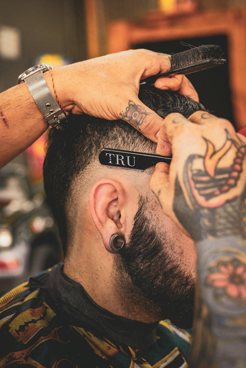 Barbier konturiert mit dem Rasiermesser Haaransatz und Bart